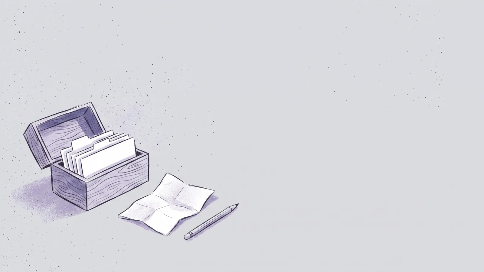 An open wooden index card box with blank cards, next to a folded sheet of paper and a pencil